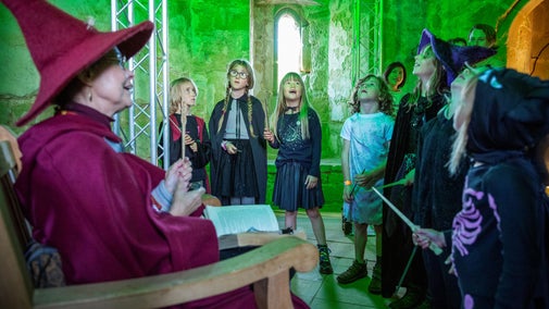 Families in fancy dress taking part in a thrilling Spell Quest to save the castle from the clutches of a wicked warlock during Halloween at Bodiam Castle, East Sussex